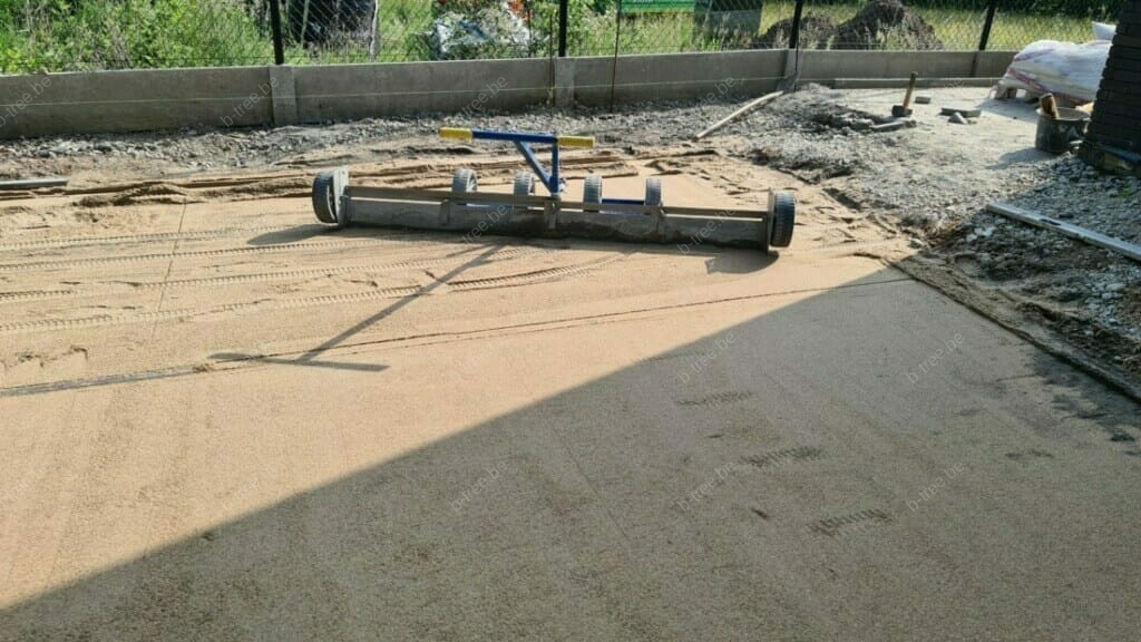 Nivelleren van de straatlaag bestaande uit rijnzand, om er de sandwichelementen, onderdeel van de groeiplaatsconstructie, er boven op te kunnen leggen. De straatlaag rijnzand ligt boven op de laag bomenzand.